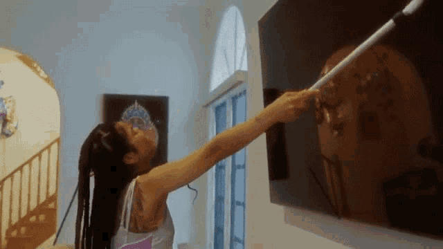 a woman with a tattoo on her arm is pointing at a picture on a wall .