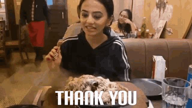 a woman is sitting at a table with a plate of food and a plate of spaghetti .