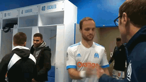 a man wearing an orange jersey shakes hands with another man