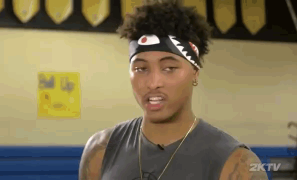a man wearing a headband with a shark on it looks at the camera .