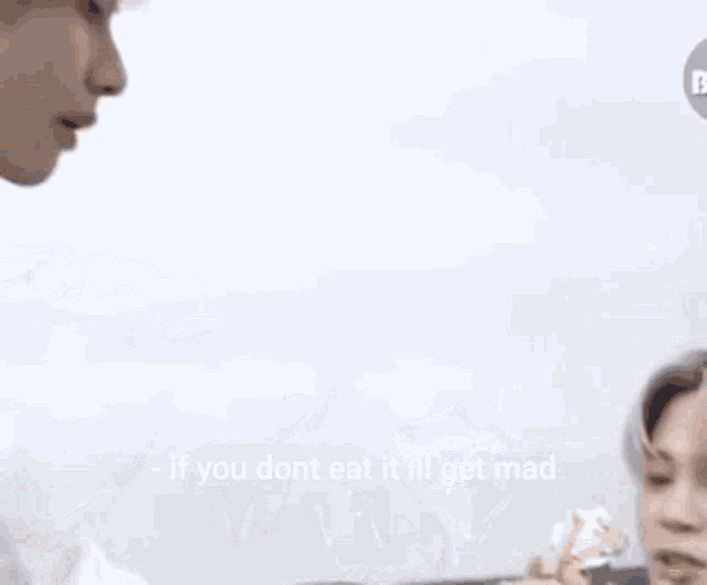 a man in a white shirt is being fed by another man with the words if you dont eat it ill get mad