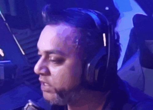 a man wearing headphones and a tie is sitting in front of a microphone .