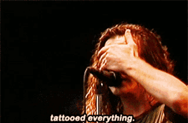 a woman singing into a microphone with the words tattooed everything written on the bottom