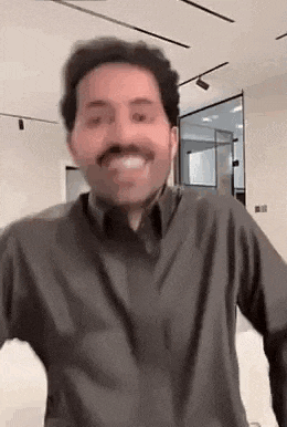 a man with a mustache is wearing a black shirt and smiling .