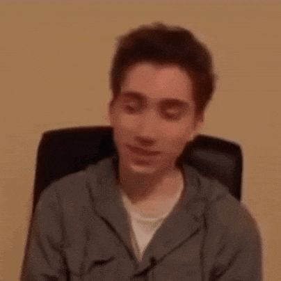 a young man is sitting in a chair and making a face .
