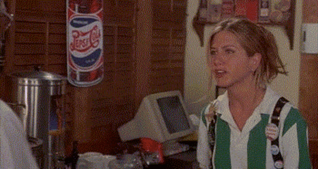 a woman in a green and white striped shirt is standing in a room with a pepsi can hanging on the wall .