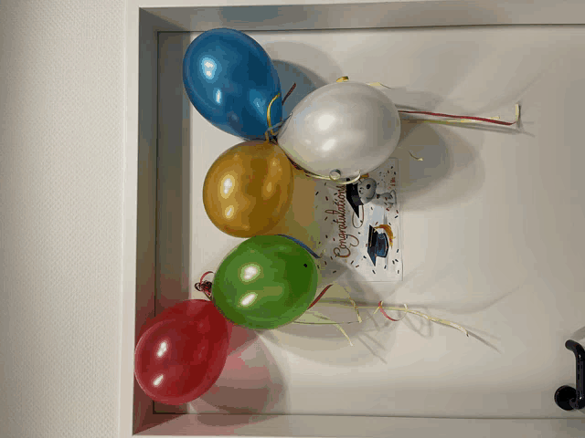 a congratulations card hangs on a door next to balloons