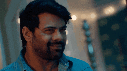 a man with a beard is wearing a blue shirt and smiling