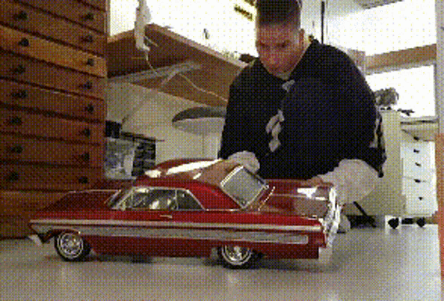 a man is playing with a model car that has the letter s on the front