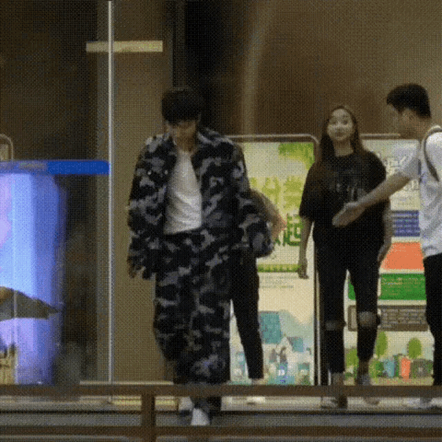 a man in a camouflage jacket is walking next to a woman in a black shirt .