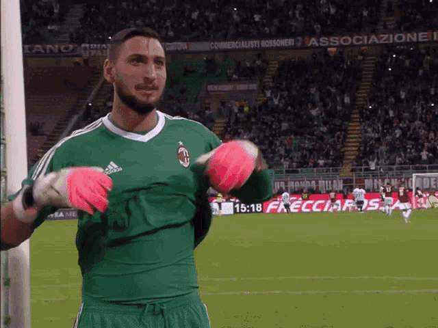 a man in a green adidas jersey holds a pink ball in his hands