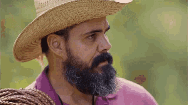 a man with a beard is wearing a cowboy hat and holding a lasso .