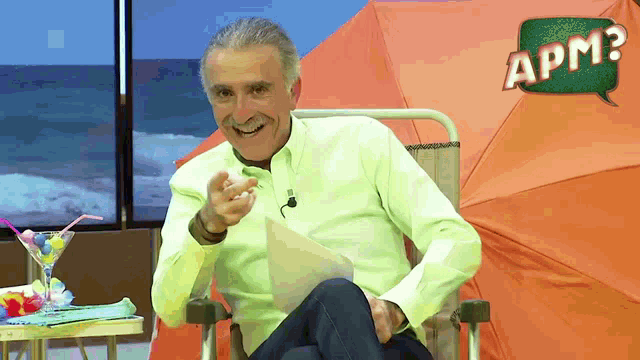 a man is sitting in front of an orange tent with a green speech bubble that says apm2