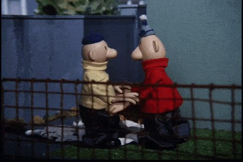 two cartoon characters standing next to each other behind a wire fence