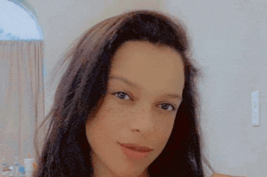 a close up of a woman 's face with long hair and freckles looking at the camera .