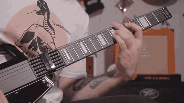 a man playing a guitar with a shirt that says recklessness