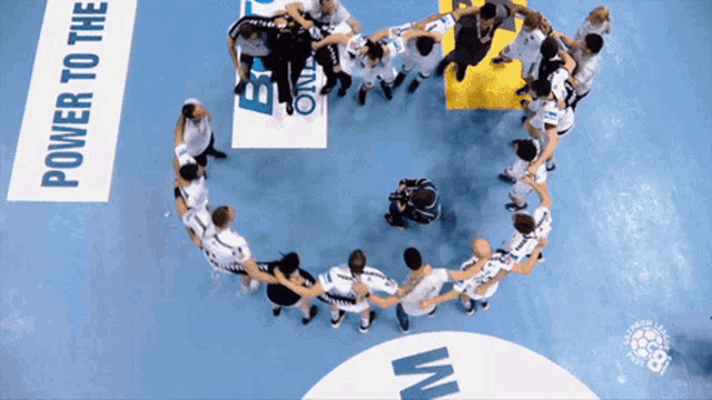 a group of people are holding hands in a circle with a power to the sign in the background