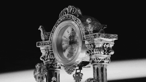 a silver clock with roman numerals on the face