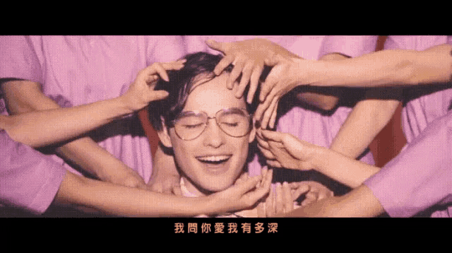 a man wearing glasses is surrounded by a group of people in purple shirts