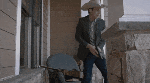 a man in a suit and cowboy hat is holding a gun
