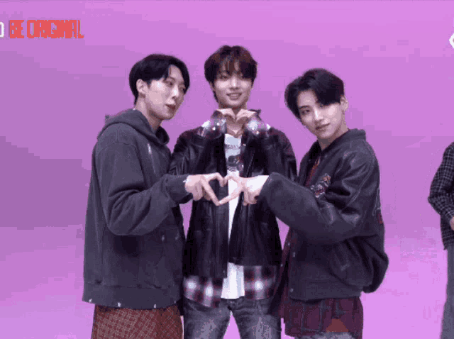 three young men are making a heart shape with their hands in front of a pink background that says be original on it