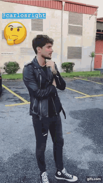 a man in a leather jacket is standing in a parking lot next to a building that says reservado