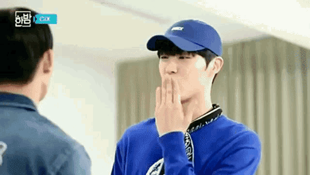 a young man wearing a blue hat is blowing a kiss .