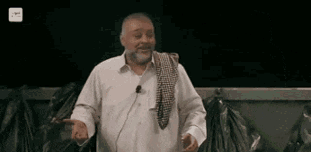 a man with a beard is standing in front of a microphone and talking .