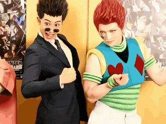 a man in a suit and tie stands next to another man in a colorful outfit
