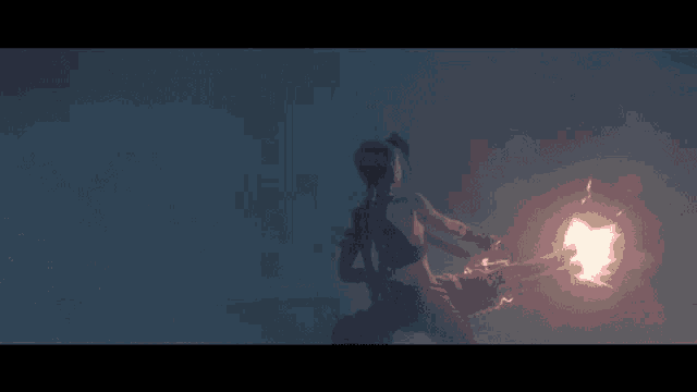 a woman is holding a glowing object in her hand in a dark room .