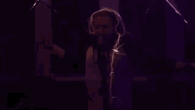 a man with headphones is singing into a microphone in a dark room .