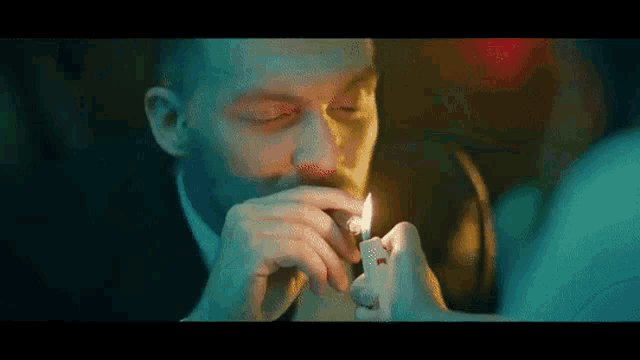 a man is lighting a cigarette with a lighter in his hand .