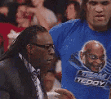 a man in a suit and tie is wearing a blue shirt that says teddy .
