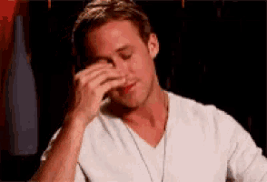 a man is covering his face with his hand while wearing a white shirt .