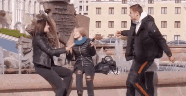 a group of people are standing next to a fountain .