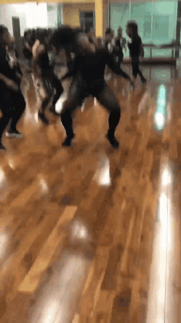 a group of people are dancing in a dance studio on a wooden floor