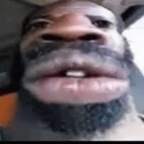 a close up of a man 's face with a beard and teeth .