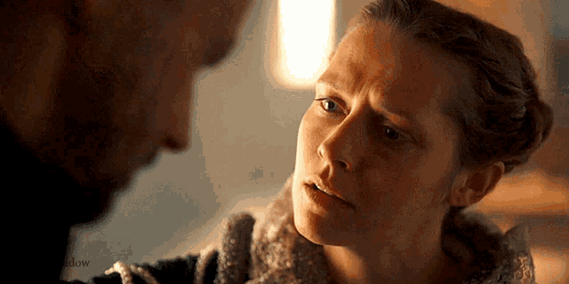 a man and a woman are looking at each other . the woman is looking at the man with a sad look on her face .