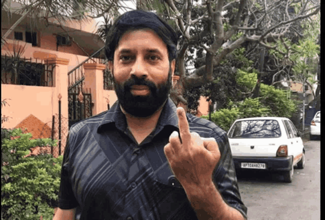 a man with a beard giving the middle finger in front of a white car