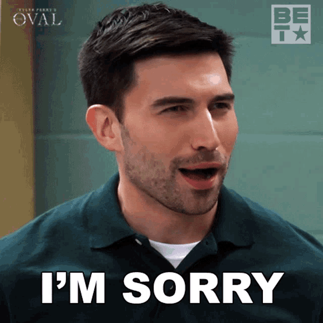 a man in a green shirt says i 'm sorry with his mouth open