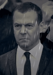 a man in a suit and tie is standing in the rain and looking at the camera