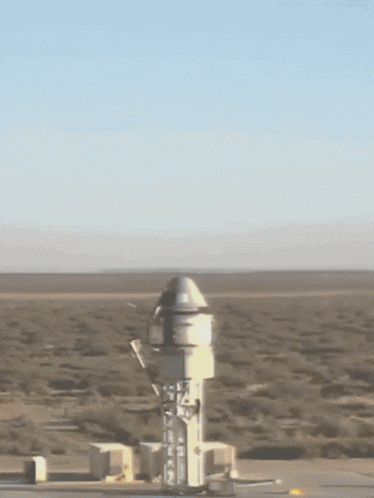 a rocket is being launched in the desert with a blue sky in the background