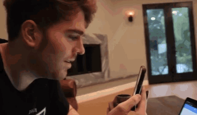a man in a jack daniels shirt is using a cell phone