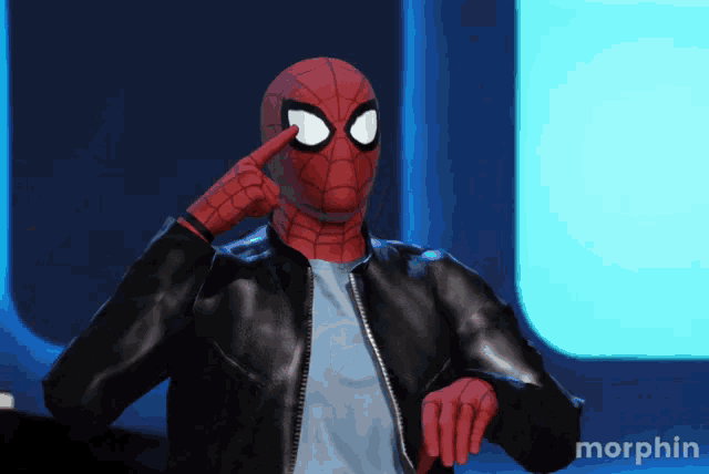 a man in a spiderman costume points to his eye
