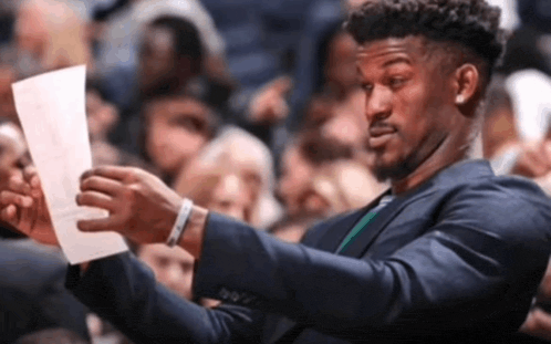 a man in a suit holds a piece of paper in his hand