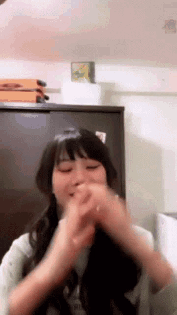 a woman is making a face with her hands in front of a refrigerator