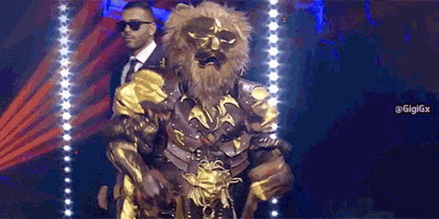 a man in a suit and tie is holding a man in a lion costume on a stage .