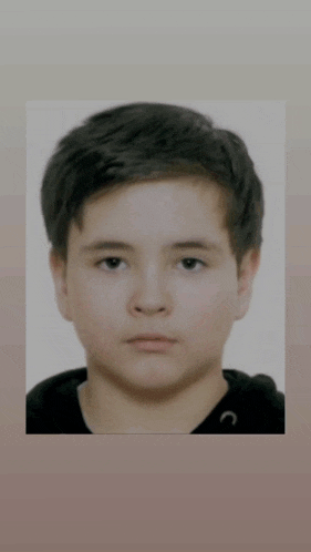 a close up of a young boy 's face with a black hoodie on