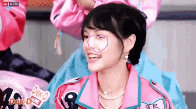 a woman in a pink jacket with a heart on her face is smiling .