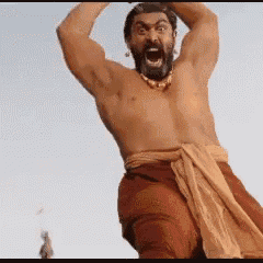 a shirtless man with a beard is standing with his arms in the air .